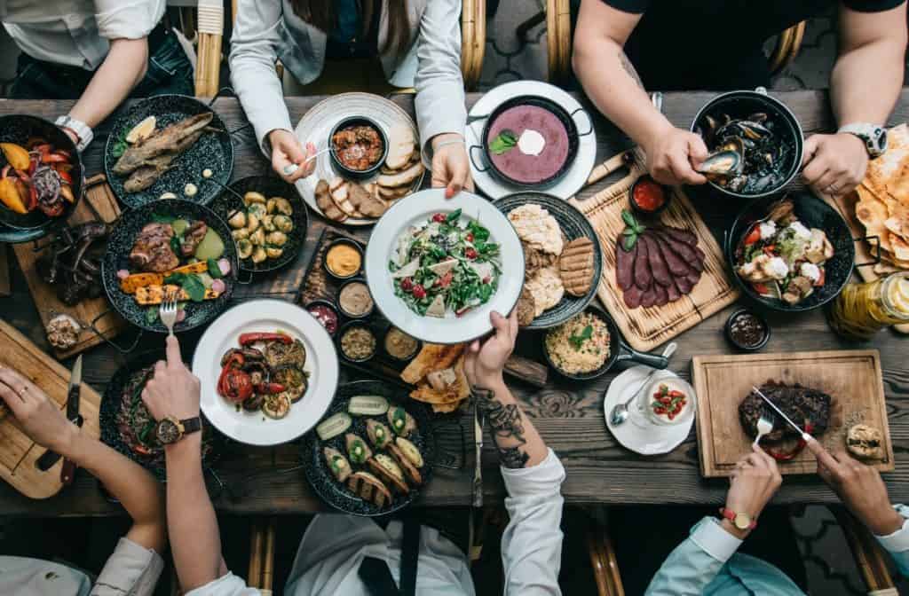 Overhead view of large table with lavish dinner with people sharing plates of food