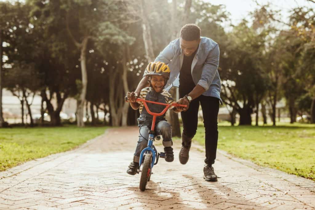 Father teaching son to ride bike at Paseo Epoca