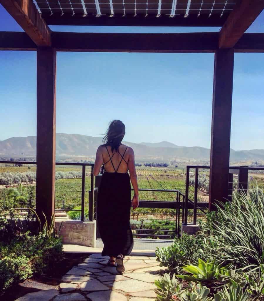 Woman on patio overlooking large farm area with mountains