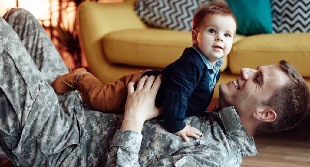 Military dad on floor playing with baby