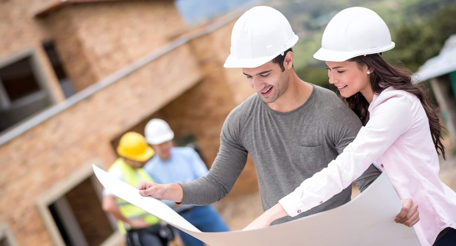 Young man and woman examining blueprints at construction site